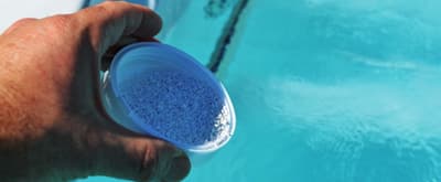 Adding,Chemicals,To,Spa person pouring bromine powder into a spa pool